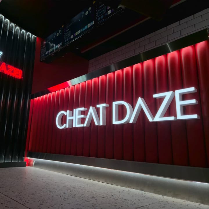 Inside a Cheat Daze dessert bar: the illuminated CHEAT DAZE sign on the red counter with LED strip glow