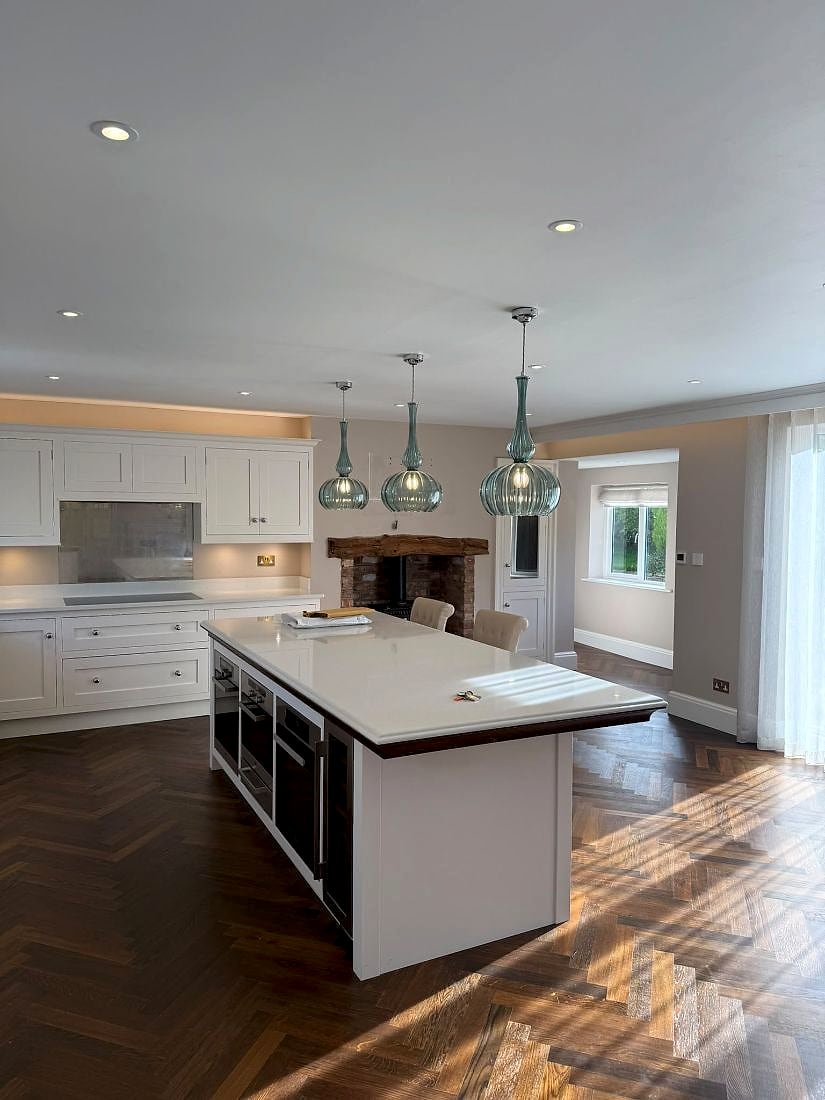 A finished kitchen with pendant lights over the island and downlights across the ceiling, fitted by Wired & Certified