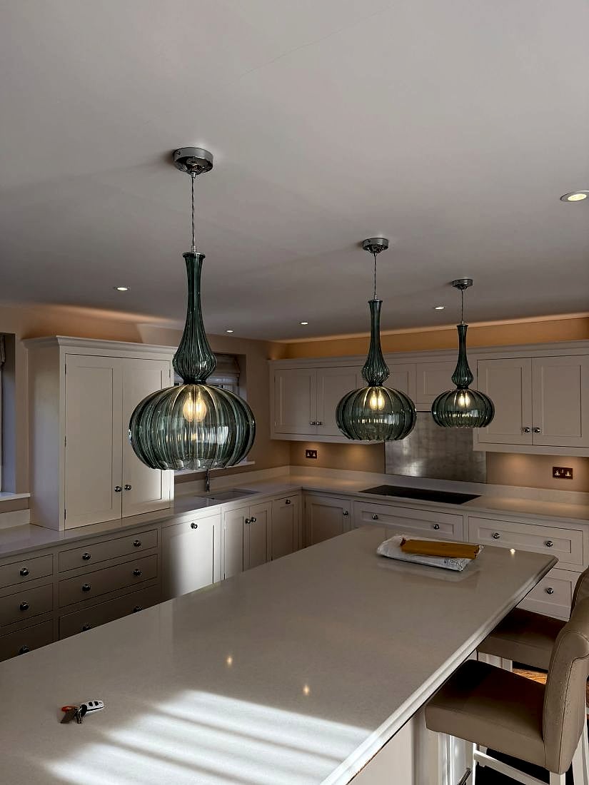 Pendant lights over a kitchen island with downlights and under-cabinet LEDs